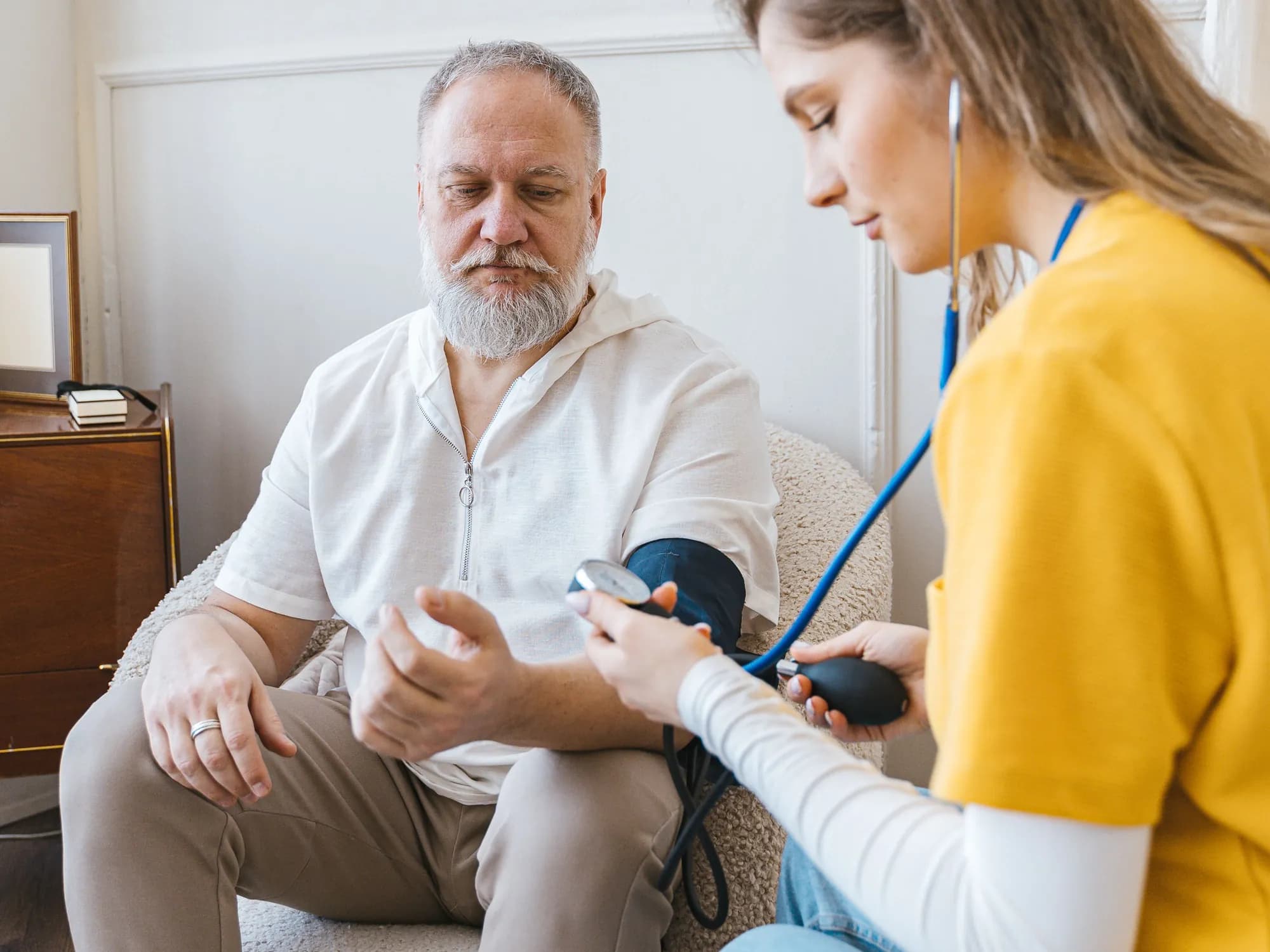 Clinician checking an adult patient's blood pressure with an arm cuff during a home visit