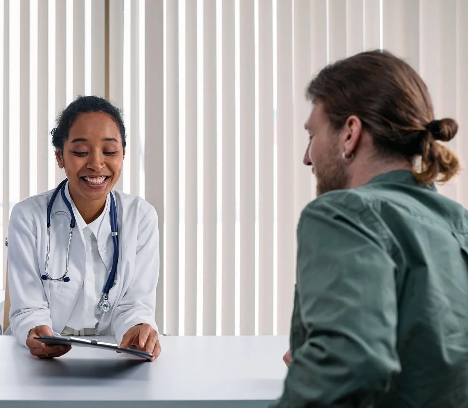 Smiling clinician going over lab results on a tablet with a client at a bright office desk