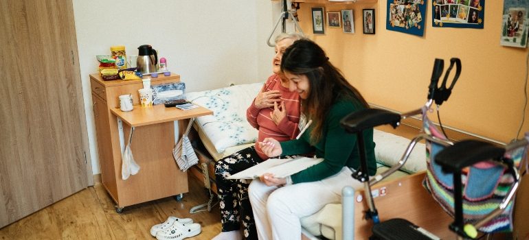 a caregiver sitting with an elderly woman reviewing paperwork